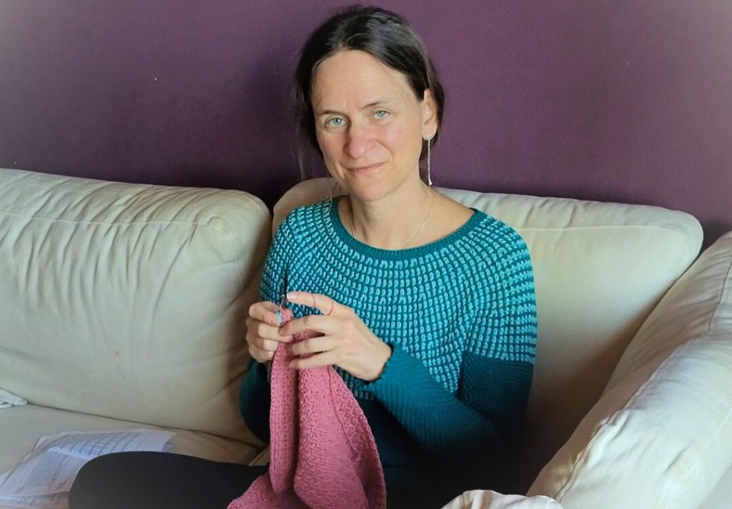 Designerin Svenjasstitches sitzt bequem auf dem Sofa und häkelt